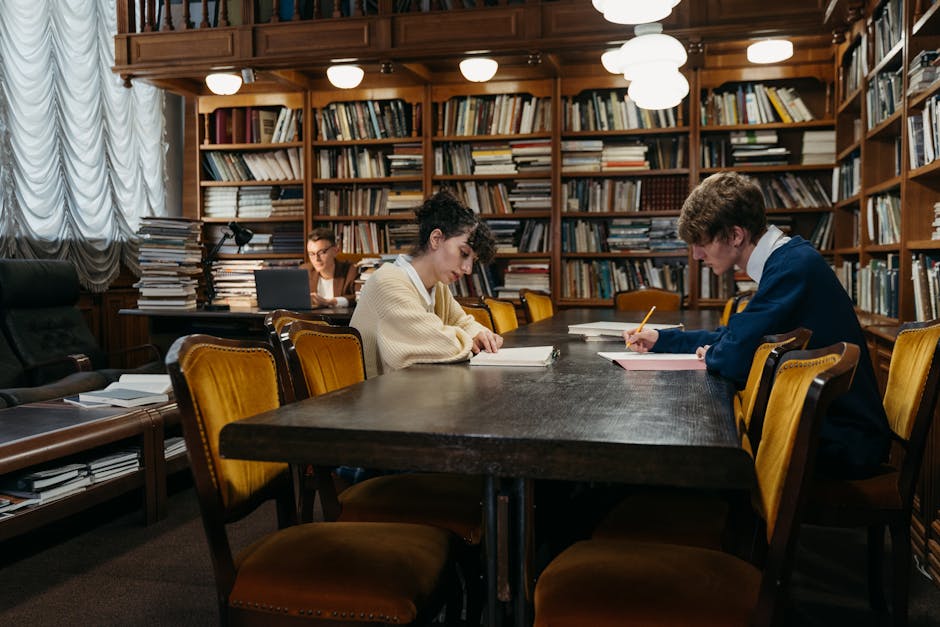 Group of students diligently studying in a traditional library filled with books, tables, and dim lighting.