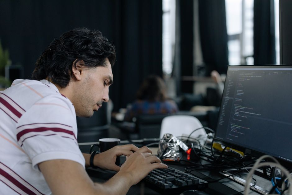 Programer intenzivno tipka na radnoj stanici u suvremenom uredskom prostoru.